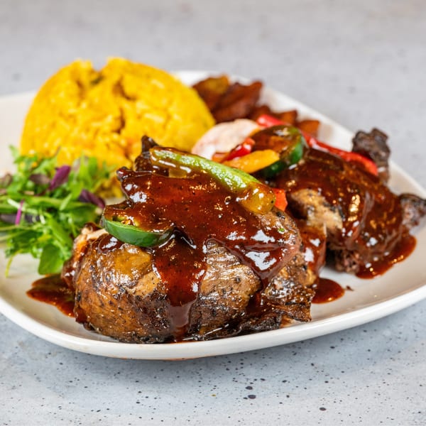 Grilled chicken with dark sauce, rice, mixed vegetables, and a side salad on a white plate.