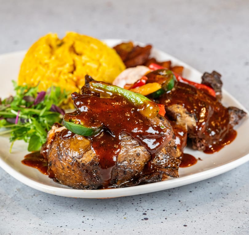 Grilled chicken with dark sauce, rice, mixed vegetables, and a side salad on a white plate.